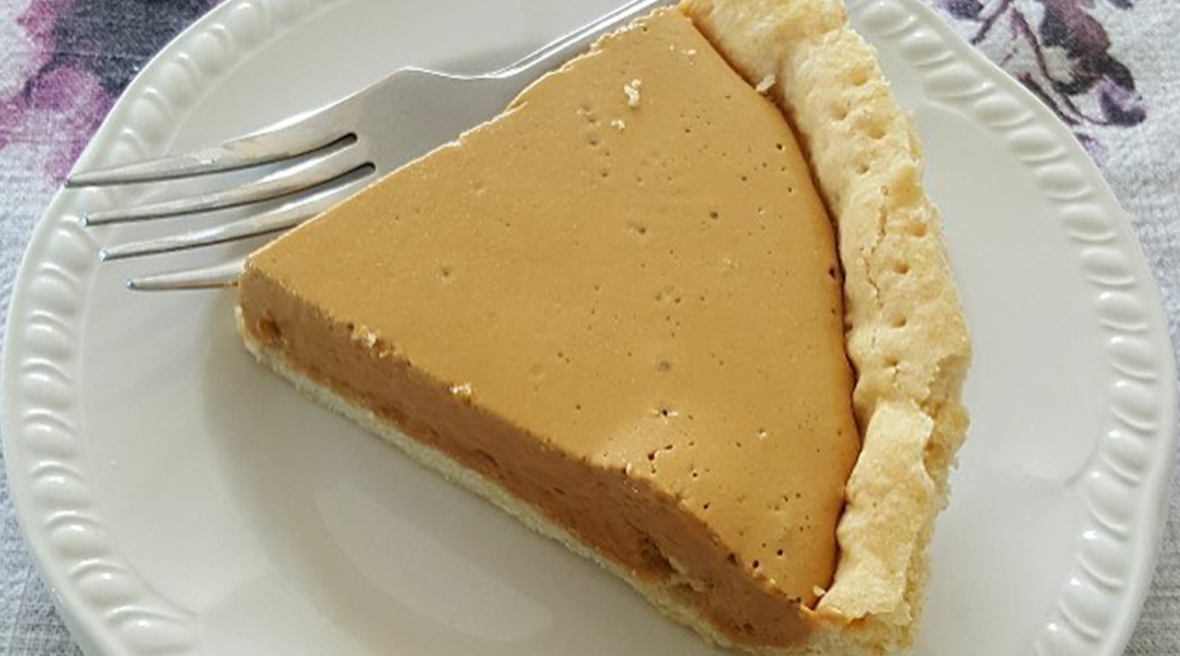 Une tarte brune et sucrée sur une assiette blanche, avec une fourchette.